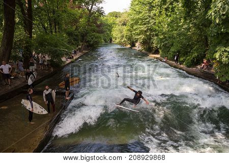 Munich, Germany, June 24, 2017: Surfers practicing their skill on an artificial wave situated on Isar river channel in Englischer garten, Munich central park, on 24th of June, 2017 in Munich, Germany.