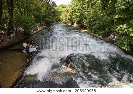 Munich, Germany, June 24, 2017: Surfers practicing their skill on an artificial wave situated on Isar river channel in Englischer garten, Munich central park, on 24th of June, 2017 in Munich, Germany.