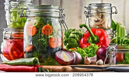 Jars With Marinated Food And Raw Vegetables On Cutting Board