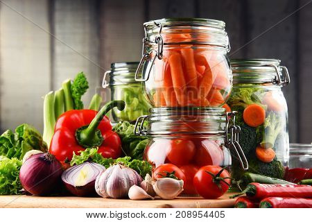 Jars With Marinated Food And Raw Vegetables On Cutting Board