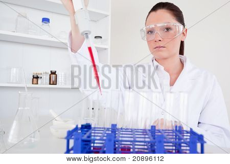 Krásný ženský biolog drží manuální pipety s vzorek ze zkumavky