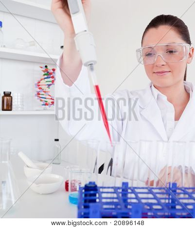 Roztomilá žena biolog drží manuální pipety s vzorek ze zkumavky