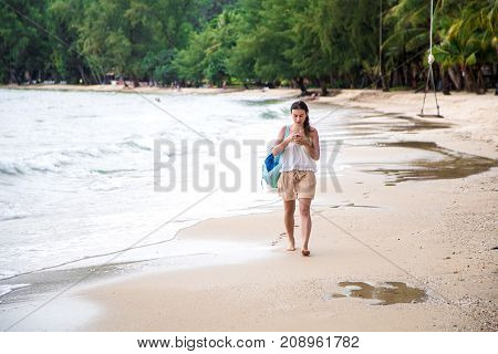 Girl Walking On The Beach With The Phone