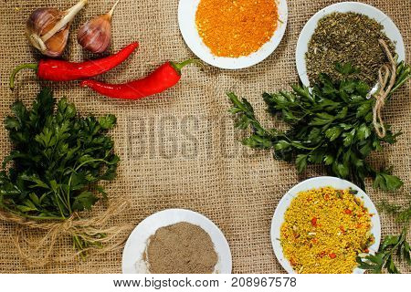 assorted spices pepper ground paprika hop schili and garlic and parsley on burlap. View from above
