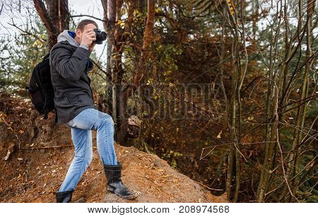 young hiker photographer photographing in autumn forest.