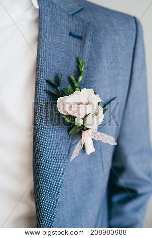 Wedding. Close up image of beautiful boutonniere on the groom's jacket. Soft focus on boutonniere. Artwork.