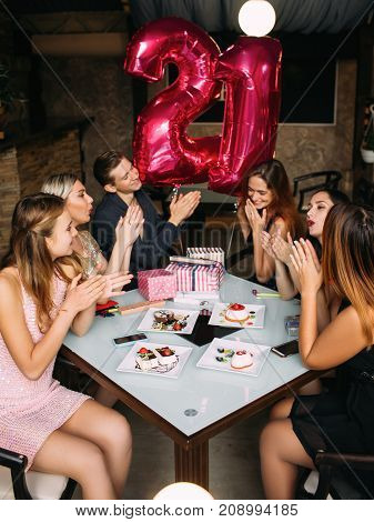 Girl 21st birthday party celebration. Friends company congratulating young female in cafe, modern youth life. Joyful mood, adulthood concept