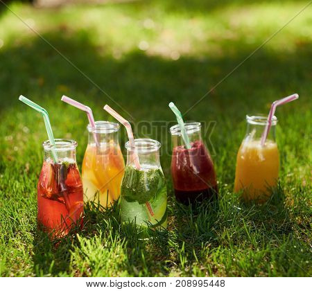 Healthy detox colourful drinks on green summer grass. Natural, fresh, organic juices and tea in bottles. Diet, well being and weight loss, superfoods, health, vegetarian food concept
