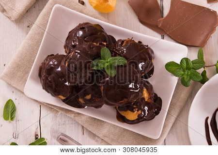 Chocolate Profiteroles With Whipped Cream On White Dish.