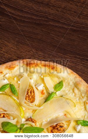 Vegetarian Italian Pizza With Nuts, Yellow Pear, Parmesan Cheese And Fresh Green Basil Leaves On A B
