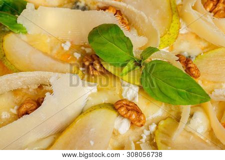 Vegetarian Italian Pizza With Nuts, Yellow Pear, Parmesan Cheese And Fresh Green Basil Leaves On A B