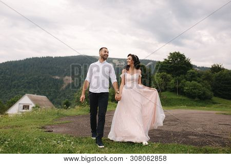 Beautiful Young Wedding Couple Standing On The Green Slope, Hill. Groom And Bride In Carpathian Moun