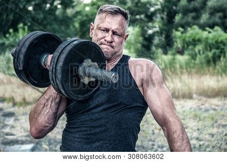 Athletic Man Working Out With A Dumbbell In Front Of Street Gym . Strength And Motivation. Outdoor W