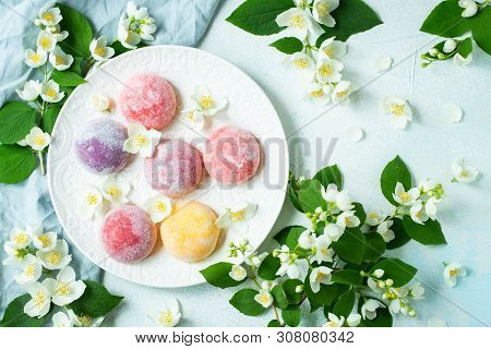 Multi-colored Japanese Ice Cream Mochi In Rice Dough And Jasmine Flowers On A Concrete Blue Backgrou