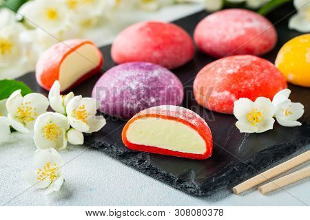 Multi-colored Japanese Ice Cream Mochi In Rice Dough And Jasmine Flowers On A Concrete Blue Backgrou