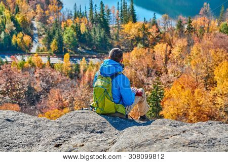 Backpacker man hiking at Artist's Bluff in autumn. View of Echo Lake. Fall colours in Franconia Notch State Park. White Mountain National Forest, New Hampshire, USA