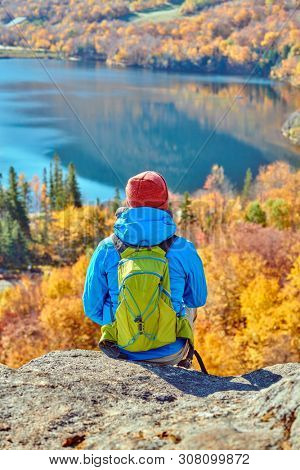 Backpacker man hiking at Artist's Bluff in autumn. View of Echo Lake. Fall colours in Franconia Notch State Park. White Mountain National Forest, New Hampshire, USA