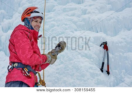 Alpinist Woman With Ice Tools Axe In Orange Helmet Climbing A L