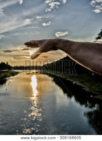 River Sun Reflection. Catch Last Sunbeam. Male Hand Pointing At Sun In Blue Sky At Evening Time Admi