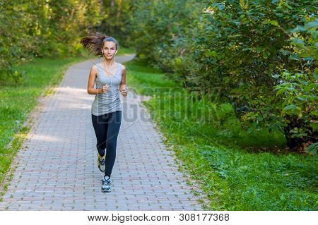 Running Woman Atletic Spotsman Trains In The Summer Park. Outdoor Fitness Portrait
