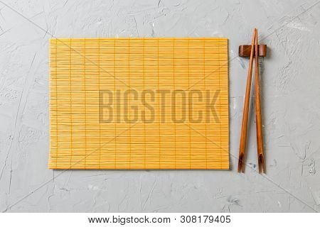 Two Sushi Chopsticks With Empty Bamboo Mat Or Wood Plate On Stone Background Top View With Copy Stac
