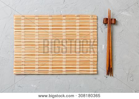 Two Sushi Chopsticks With Empty Bamboo Mat Or Wood Plate On Stone Background Top View With Copy Stac