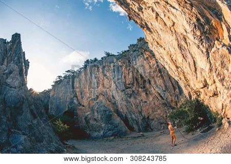Athletic Man Climbs A Rock, 7c Category Route In The Forest With Rope, Against Sunset And The Other 