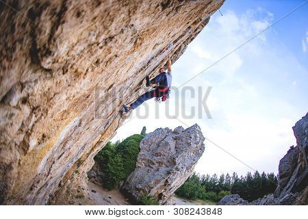 Athletic Man Climbs A Rock, 7c Category Extreme Overhanging Route In The Forest With Rope. Sport Cli
