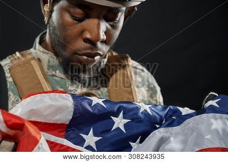 Close Up Of American Soldier In Helmet And Uniform Sadly Looking And Crying Under National Flag. Ran