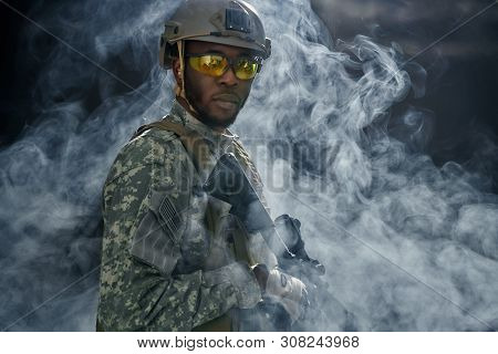 View From Cloud Of Smoke Of American Soldier In Glasses And Helmet Looking At Camera. African Ranker