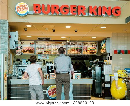 Stuttgart, Germany - Aug 15, 2018: Rear View Of Senior And Adult Customers At The Counter Of Burger 