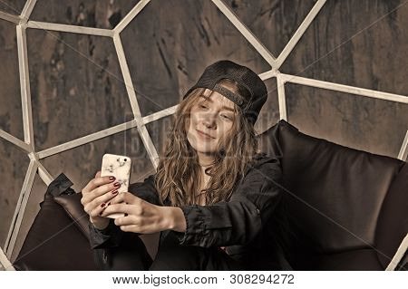 Woman Or Girl In Baseball Cap Making Selfie With Smartphone On Brown Chair. Technology And Mobile De
