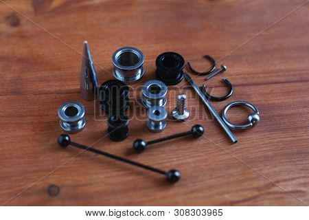 Jewelry Piercing Set. Piercing Accessories On Wooden Background. Stretching For Ear Tunnels , A Cath
