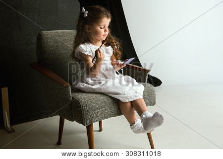 Interaction Of Children With Adult World. Cute Girl Trying To Do Bright Make Up For Being Older. Lit