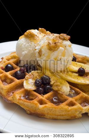 Gofre - Belgian Homemade Waffles With Ice Cream, Bananas And Nuts On A White Plate