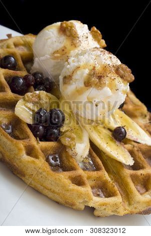 Gofre - Belgian Homemade Waffles With Ice Cream, Bananas And Nuts On A White Plate