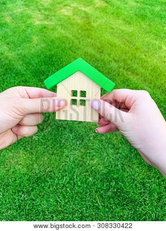 Wooden House In The Hand Of A Young Family. Buying A Home In A Mortgage Loan. Real Estate Concept. E
