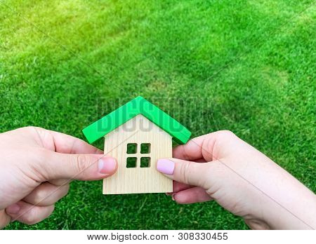 Wooden House In The Hand Of A Young Family. Buying A Home In A Mortgage Loan. Real Estate Concept. E