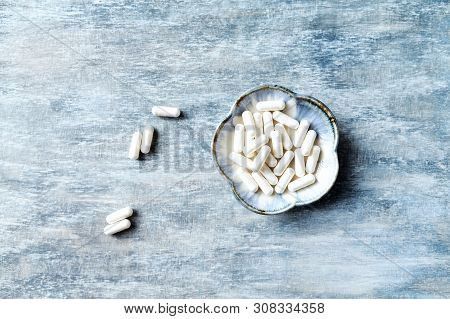 Theanine Capsules. Dietary Supplement.   Rustic Wooden Background. Top View. Copy Space.