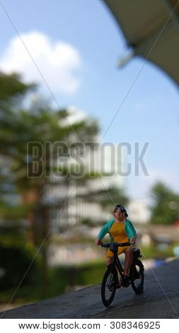 Close Up Mini Figure Woman Toys Bicycling At Building Gate With Negative Or Copy Space For Text Area