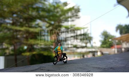 Close Up Mini Figure Woman Toys Bicycling At Building Gate With Negative Or Copy Space For Text Area
