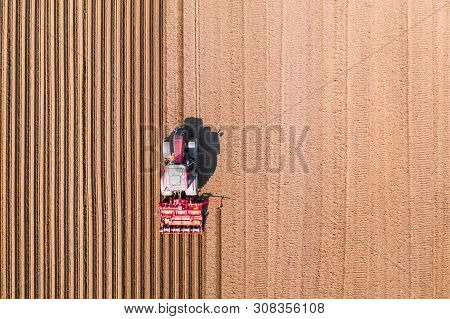Tractor With Disc Harrows On Farmland, Top View. Tractor Cuts Furrows In A Plowed Field. Preparing T