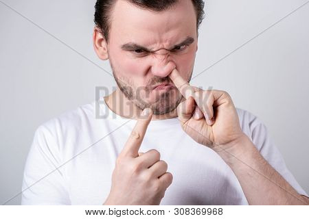 Handsome Brunette Guy With Bristles In A White T-shirt Picks His Finger In His Nose