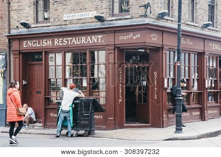 London, Uk - June 15, 2019: Employee Throwing Away Rubbish Outside The English Restaurant In Shoredi