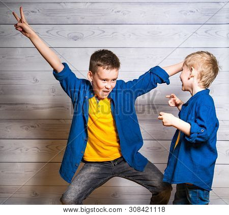 Happy And Friendly Brothers During The Game Isolated In Studio. One Elder Boy Is Showing Funny Pose 