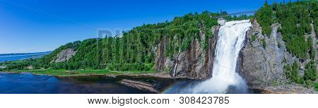 Beautiful Montmorency Falls With Rainbow And Blue Sky. View Of Canadian Fall Located Near Quebec Cit