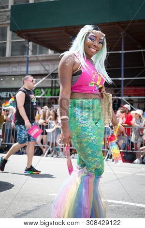 2018 JUNE 24 NEW YORK: NYC Pride March participants wearing pink and rainbow colored T-Mobile shirts walk along the 5th Ave parade route.
