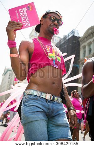 2018 JUNE 24 NEW YORK: NYC Pride March participants wearing pink and rainbow colored T-Mobile shirts walk along the 5th Ave parade route.