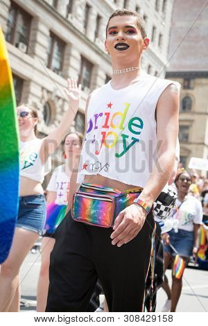 2018 JUNE 24 NEW YORK: NYC Pride March participants walk behind the Macys Pride and Joy banner on the 5th Ave parade route.