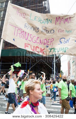 2018 JUNE 24 NEW YORK: NYC Pride March participant walks with a banner that says This Lesbian Mama Roars Proud For Her Transgender Son on the 5th Ave parade route.